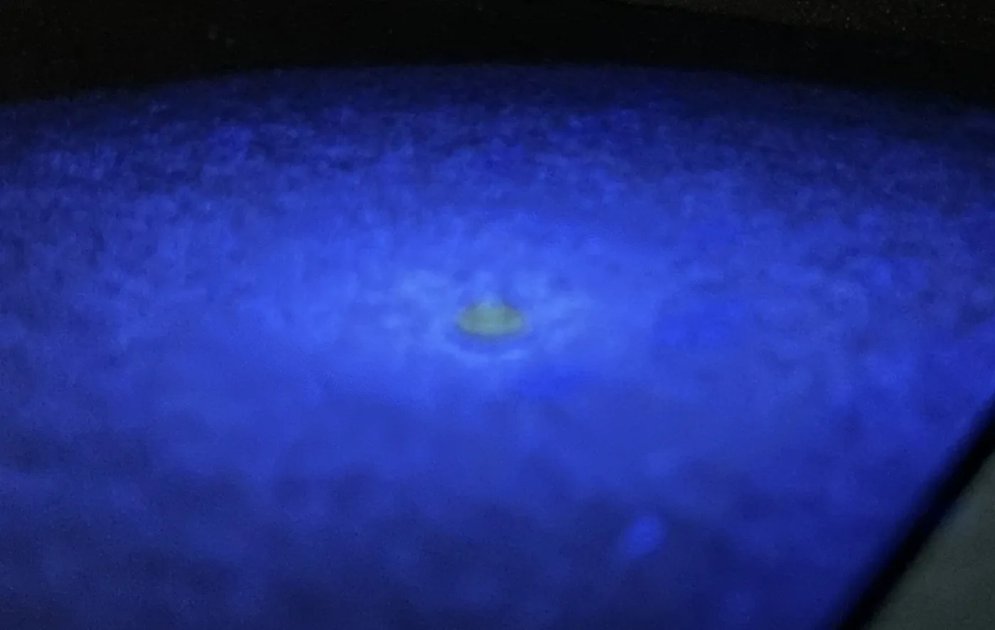 Derselbe HPHT-Diamant unter kurzwelligem UV-Licht: Der Stein leuchtet grünlich-gelb
