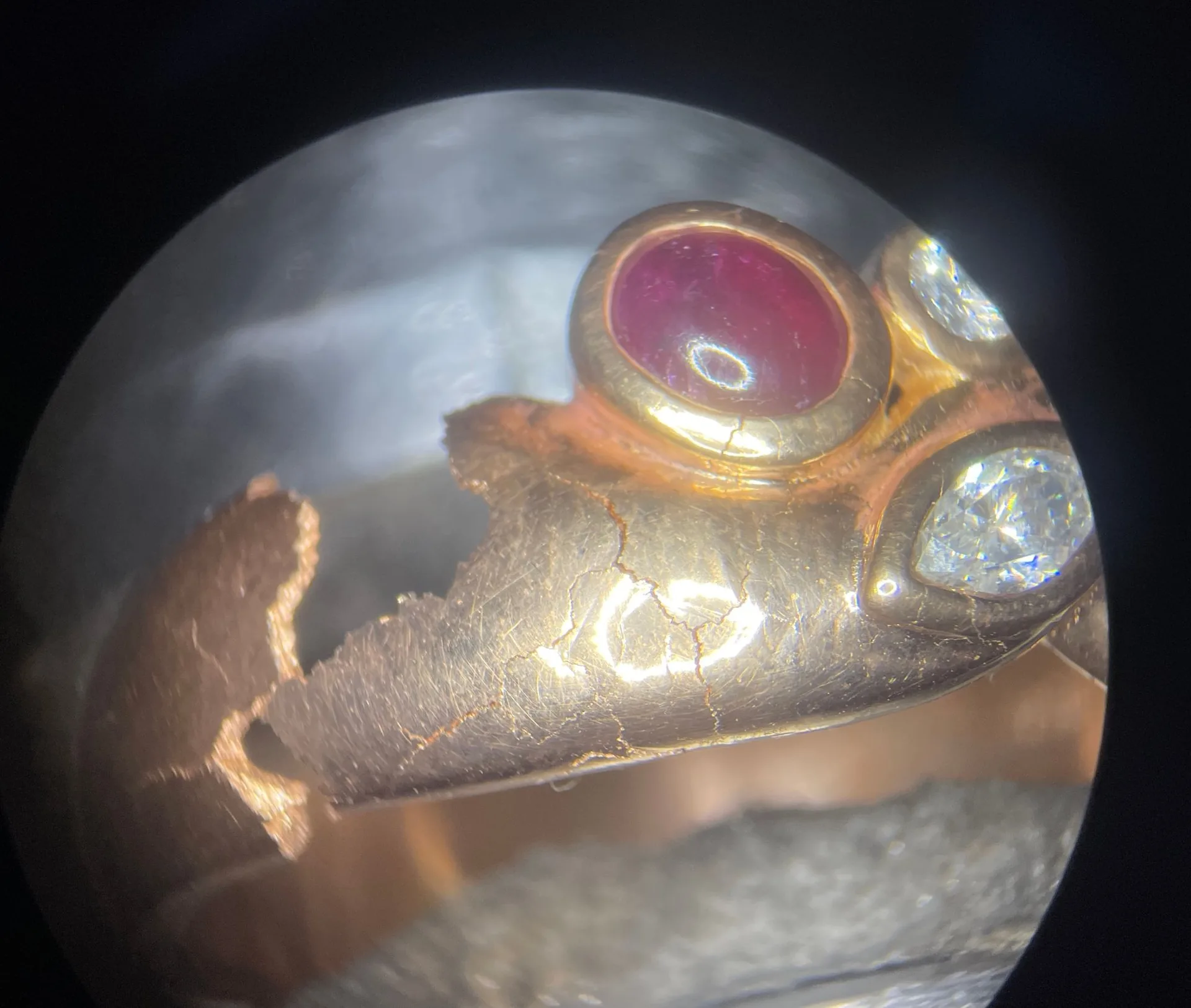 Ring mit Rubin-Cabochon und Diamanten unter dem Mikroskop, Rissnetz und ausgebrochene Schiene
