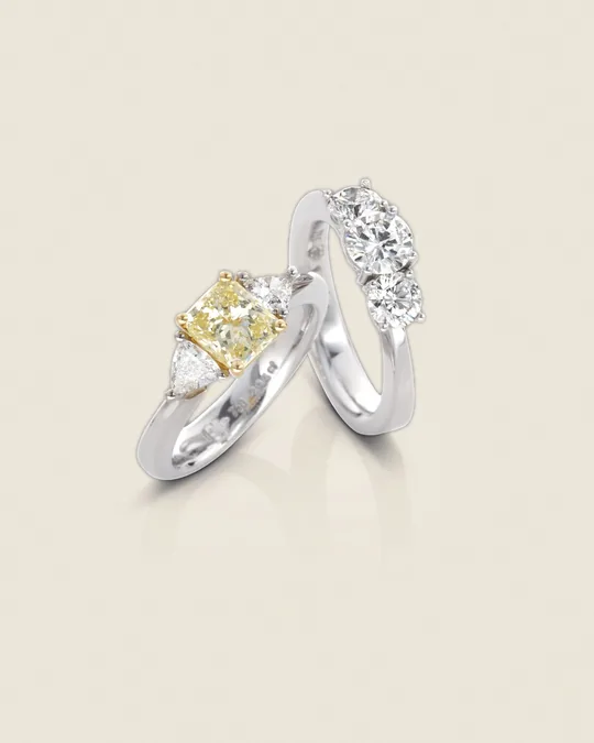 Zwei Dreistein-Ringe, einer mit gelbem Diamanten, einer mit drei weißen Diamanten